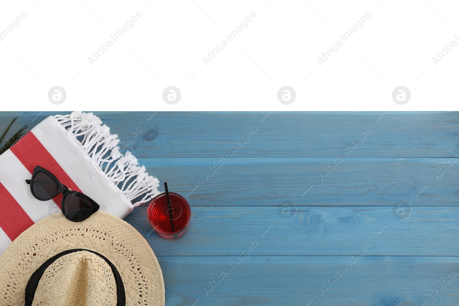 Photo of Light blue wooden surface with beach towel, straw hat, refreshing drink and sunglasses on white background, top view. Space for text