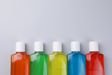 Photo of Fresh mouthwashes in bottles on grey background, flat lay. Space for text