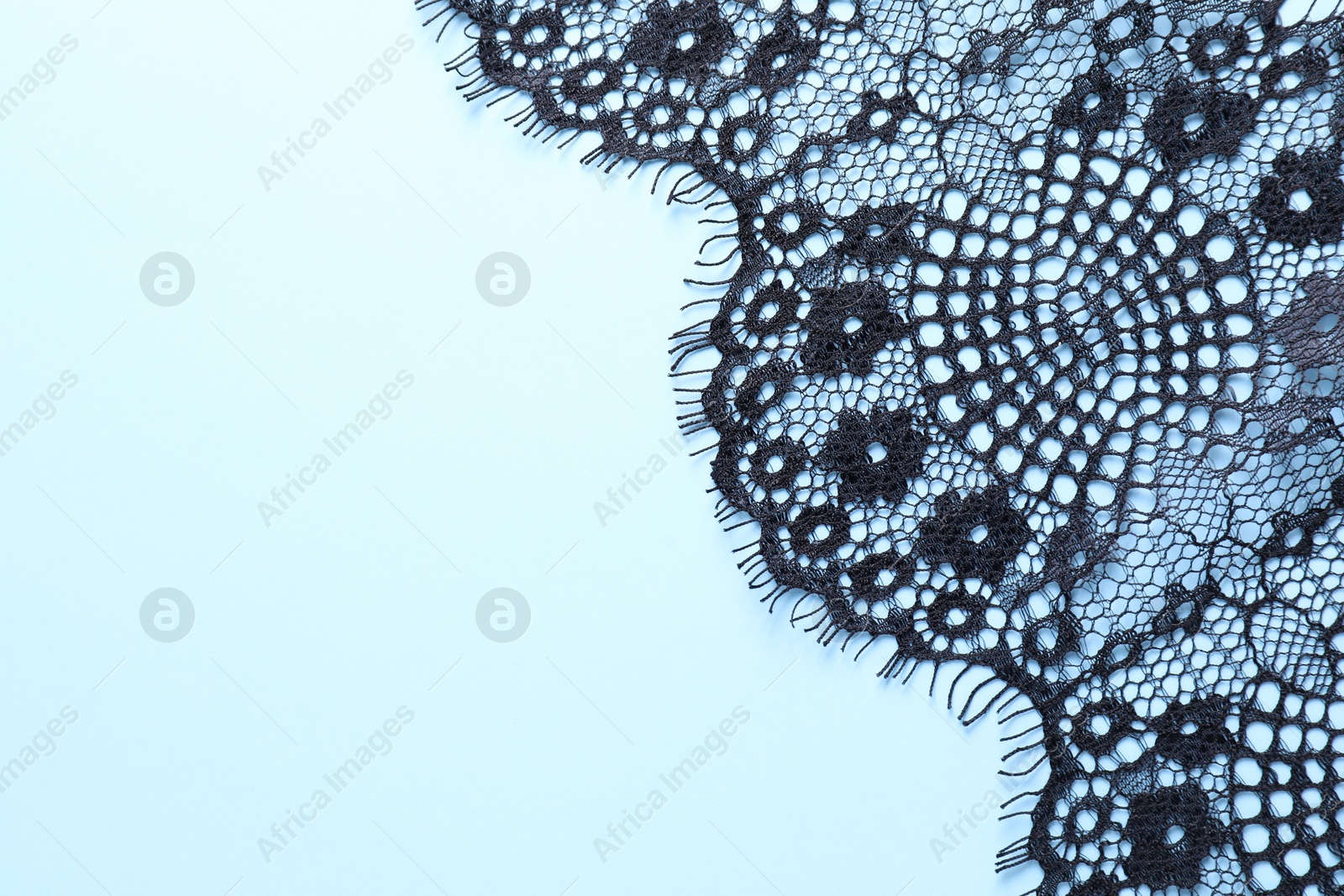 Photo of Black lace on light blue background, top view. Space for text