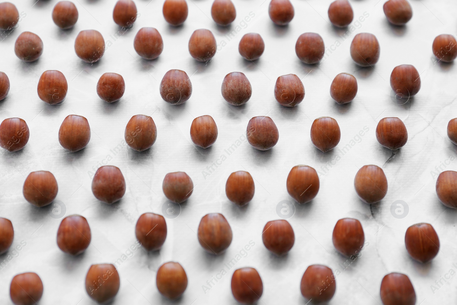 Photo of Brown tasty hazelnuts on light marble table