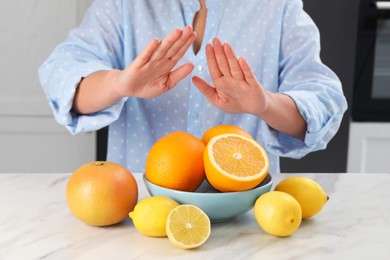 Photo of Woman suffering from food allergies refusing eat citrus fruits at light marble table indoors, closeup