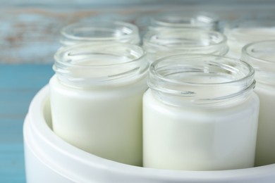 Photo of Modern yogurt maker with full jars, closeup