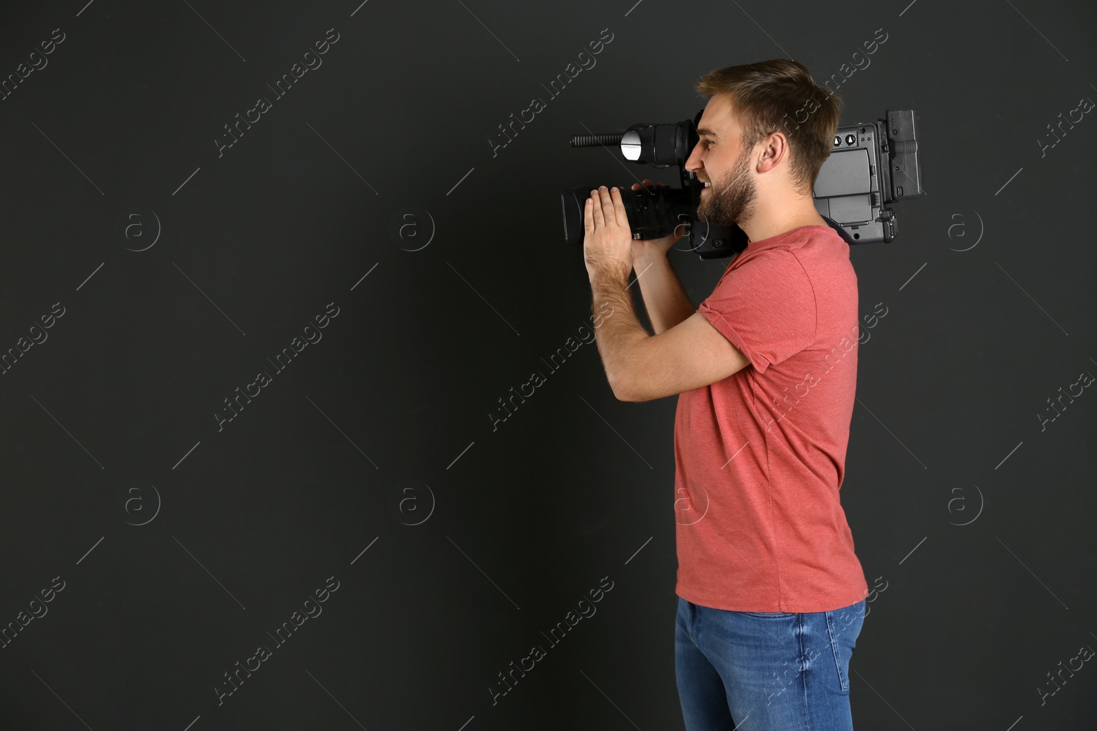 Photo of Operator with professional video camera on black background, space for text