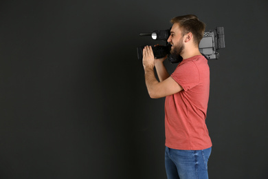 Photo of Operator with professional video camera on black background, space for text