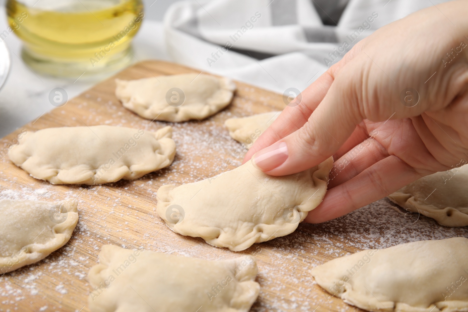 Photo of Woman making dumplings (varenyky) with tasty filling at table, closeup