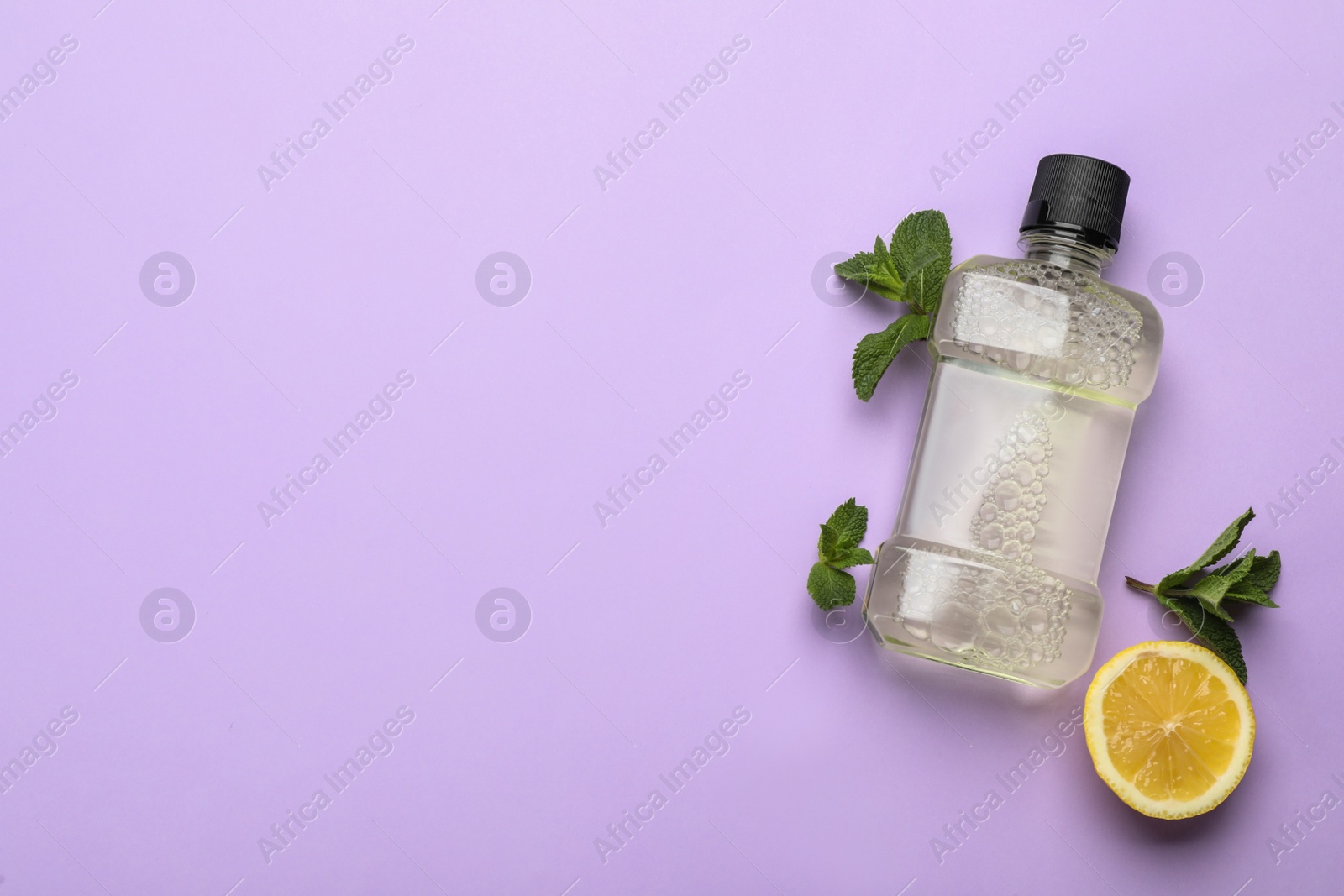 Photo of Mouthwash, mint and lemon on violet background, flat lay. Space for text