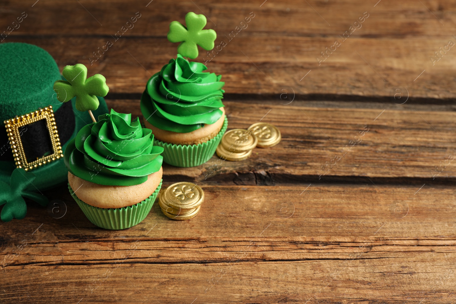 Photo of Composition with delicious decorated cupcakes on wooden table, space for text. St. Patrick's Day celebration