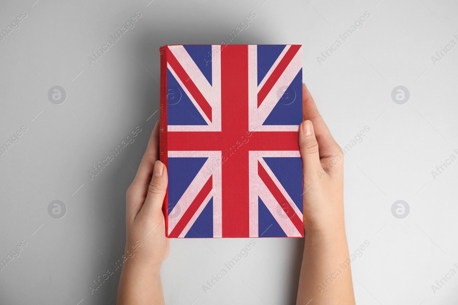 Image of Woman with book on light grey background, top view. Learning English