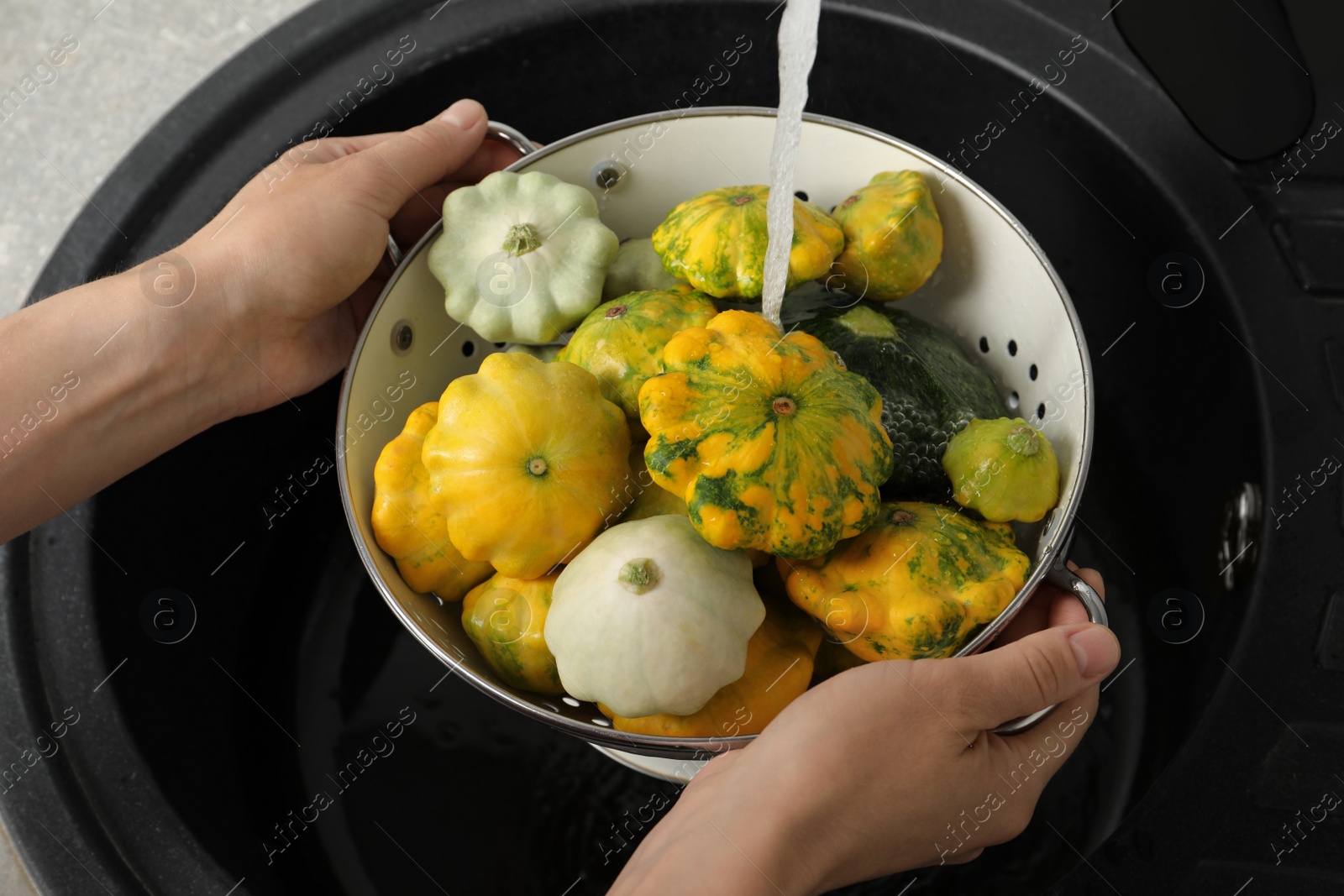 Photo of Woman washing pattypan squashes above sink, closeup