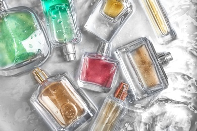 Different perfume bottles in water, flat lay