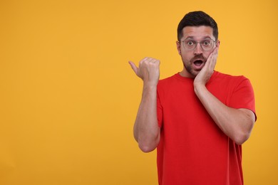 Photo of Special promotion. Emotional man pointing at something on orange background. Space for text