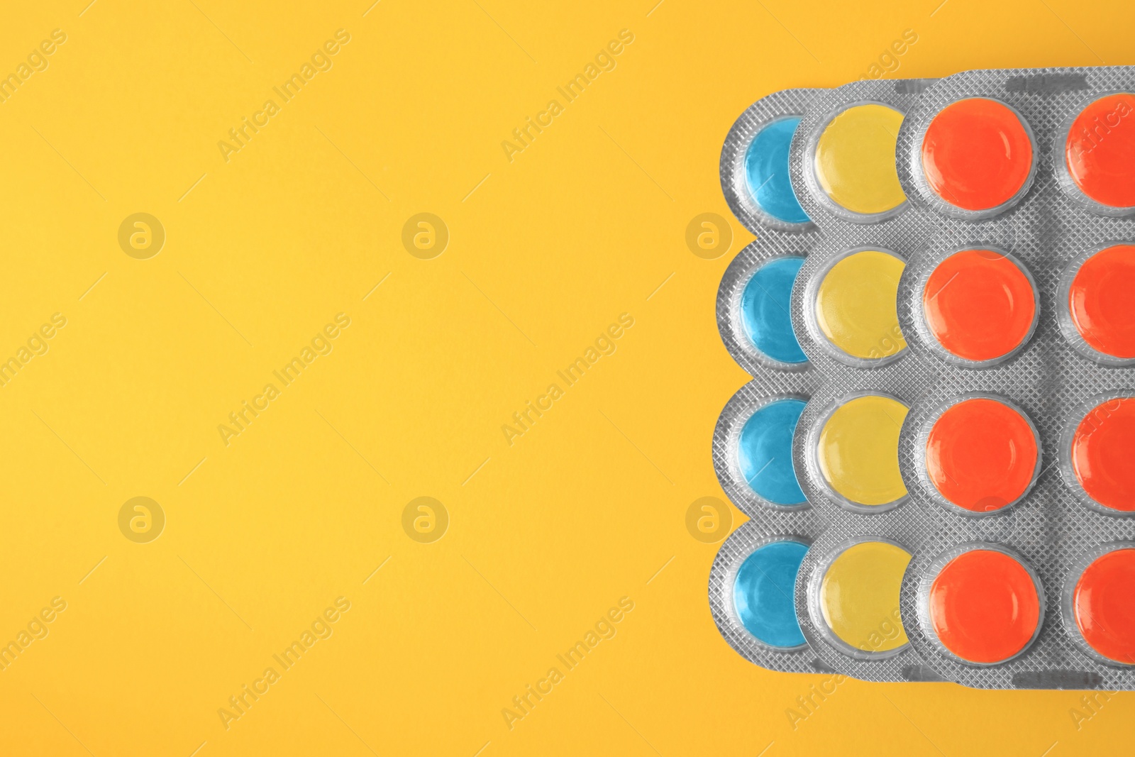 Photo of Blisters with cough drops on yellow background, flat lay. Space for text