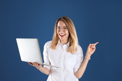 Portrait of young woman in office wear with laptop on color background