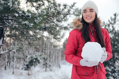 Photo of Young woman holding snowball outdoors on winter day. Space for text