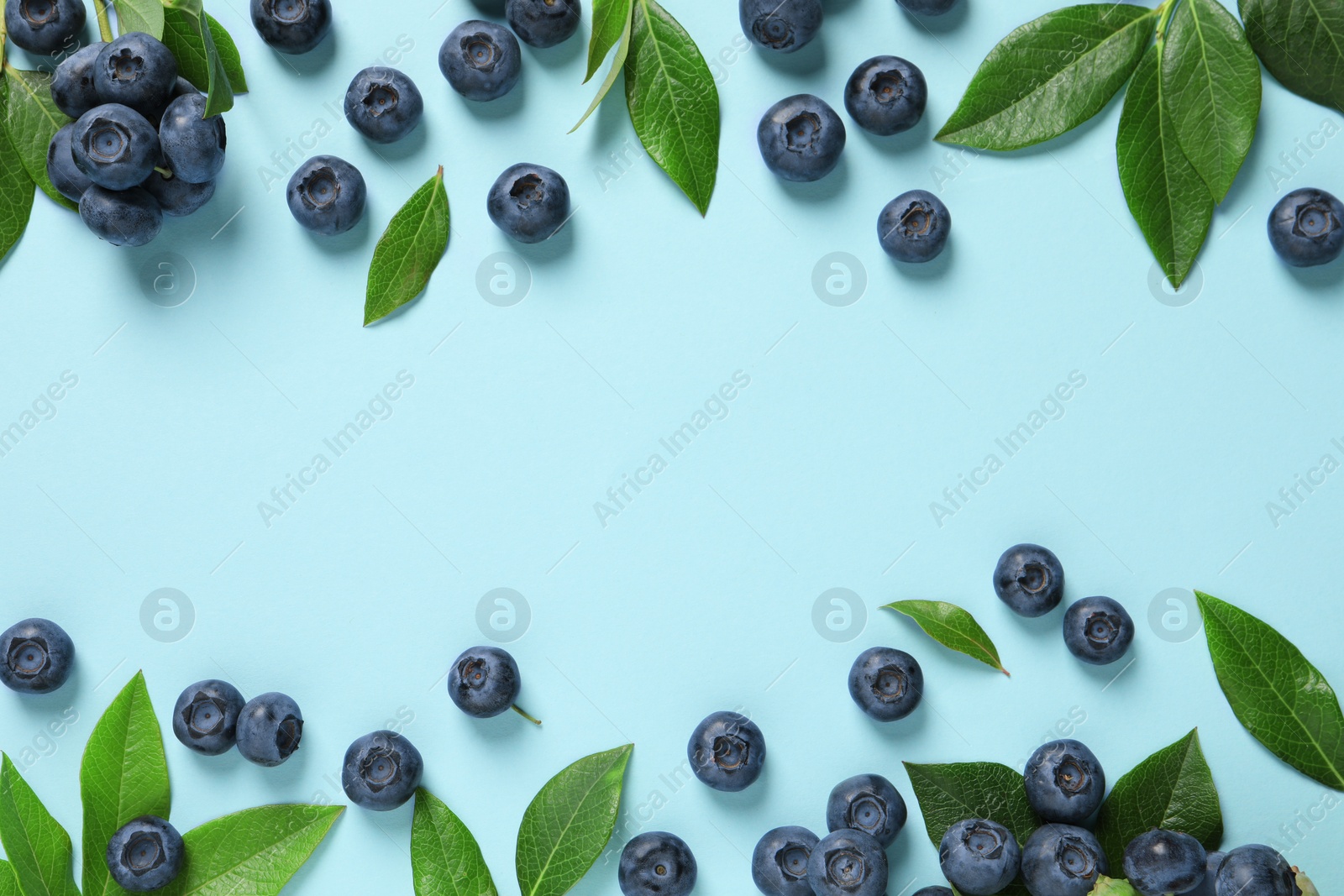 Photo of Tasty fresh blueberries with green leaves on light blue background, flat lay. Space for text