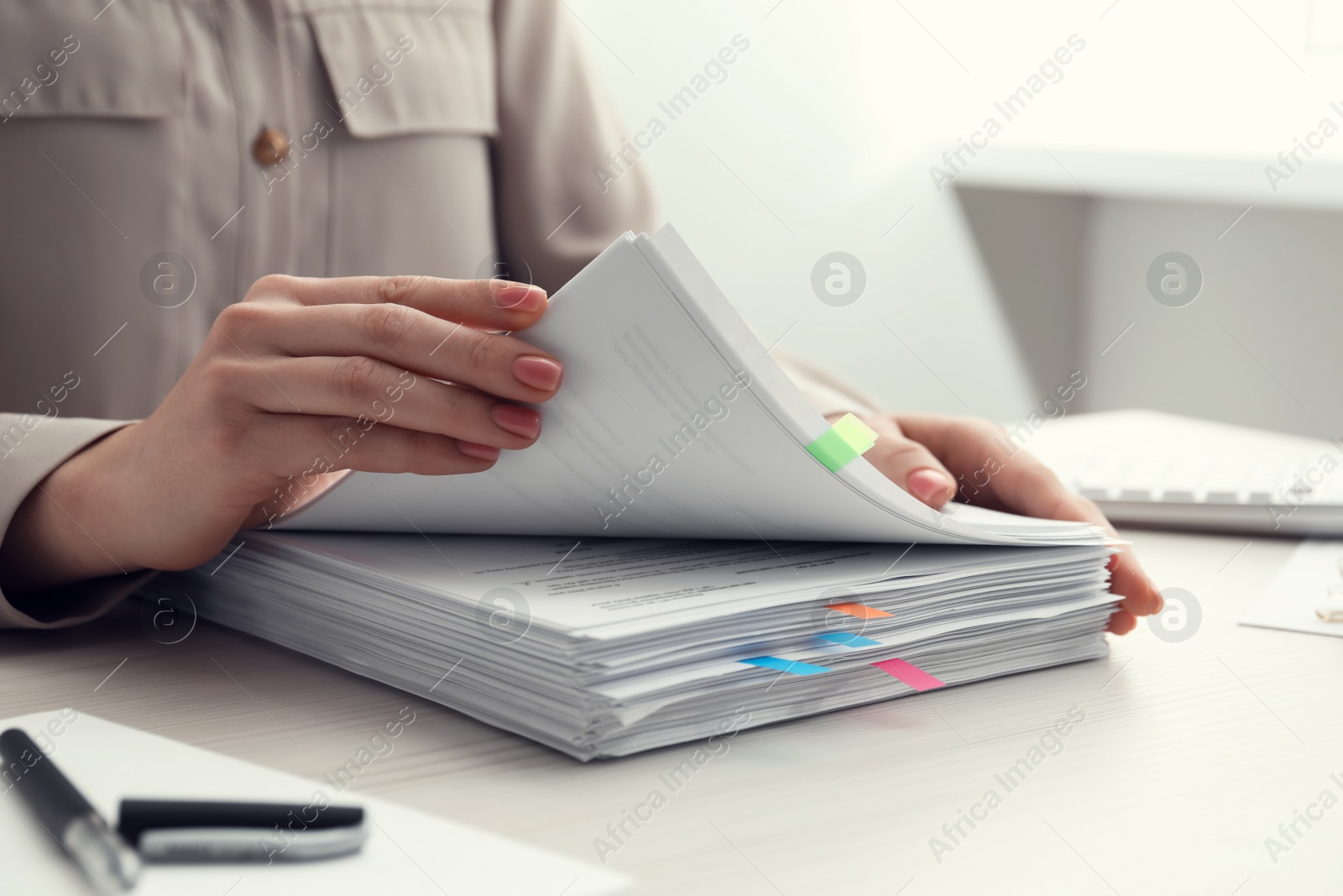 Photo of Woman reading documents at wooden table in office, closeup