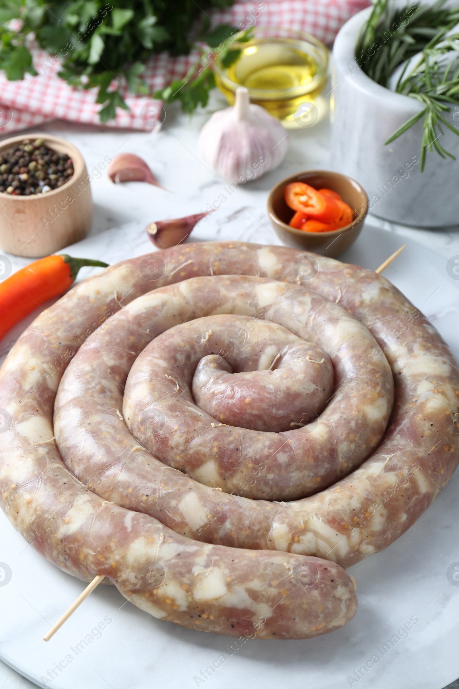 Photo of Raw homemade sausage on white marble table, closeup