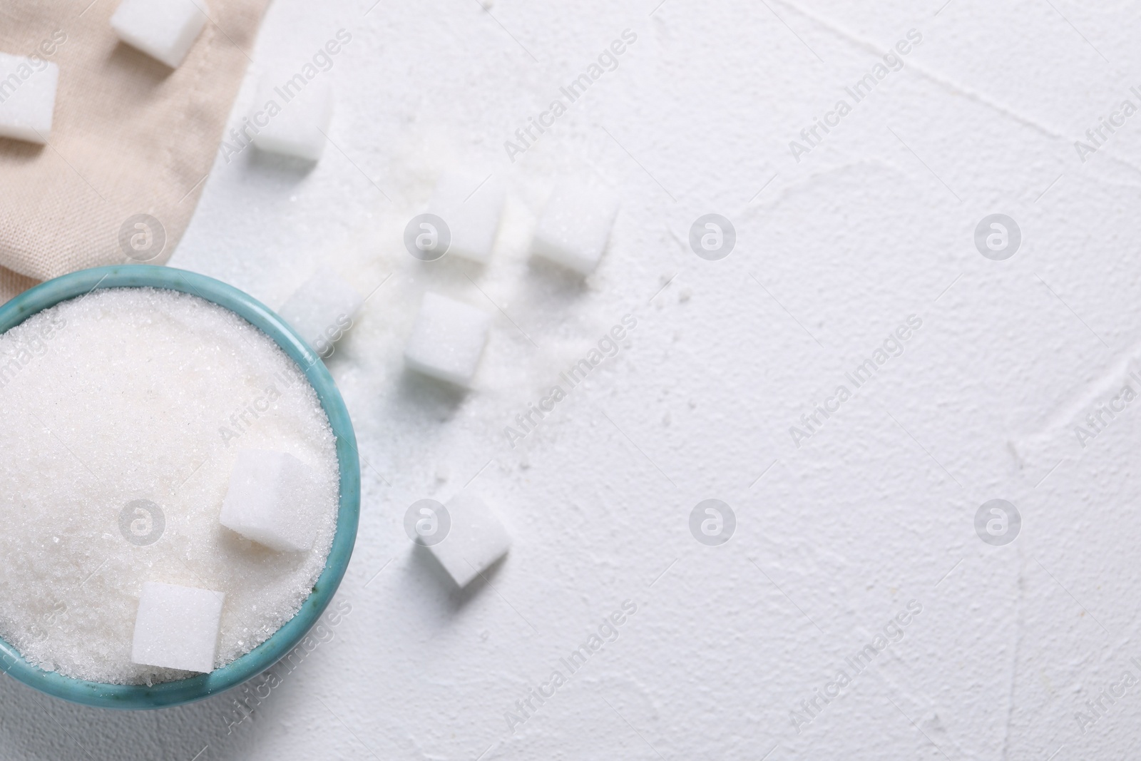 Photo of Different types of sugar in bowl on white table, flat lay. Space for text