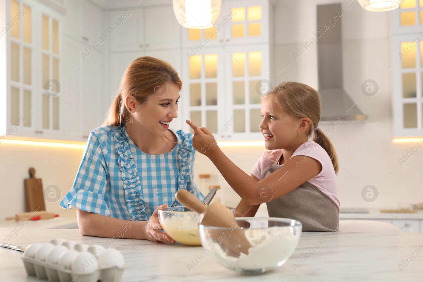 Photo of Mother and daughter making dough together in kitchen