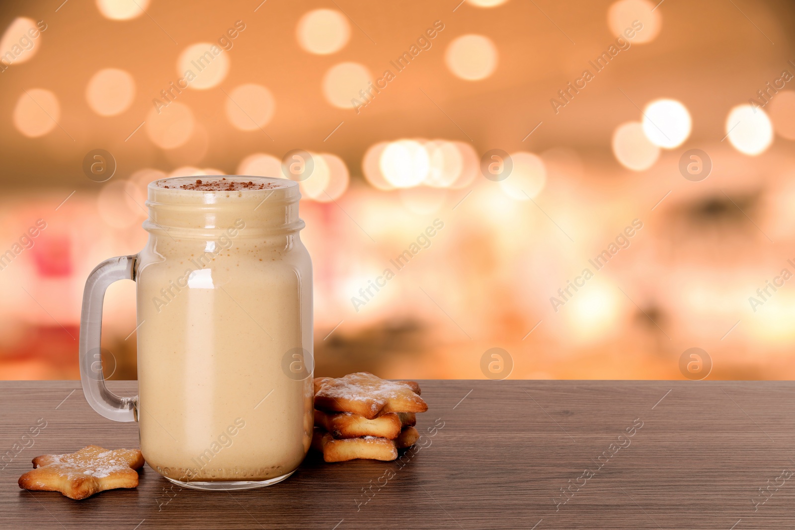 Image of Mason jar with delicious eggnog and cookies on wooden table in bar, space for text