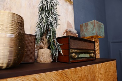 Retro radio and small decorative Christmas tree on cabinet in room