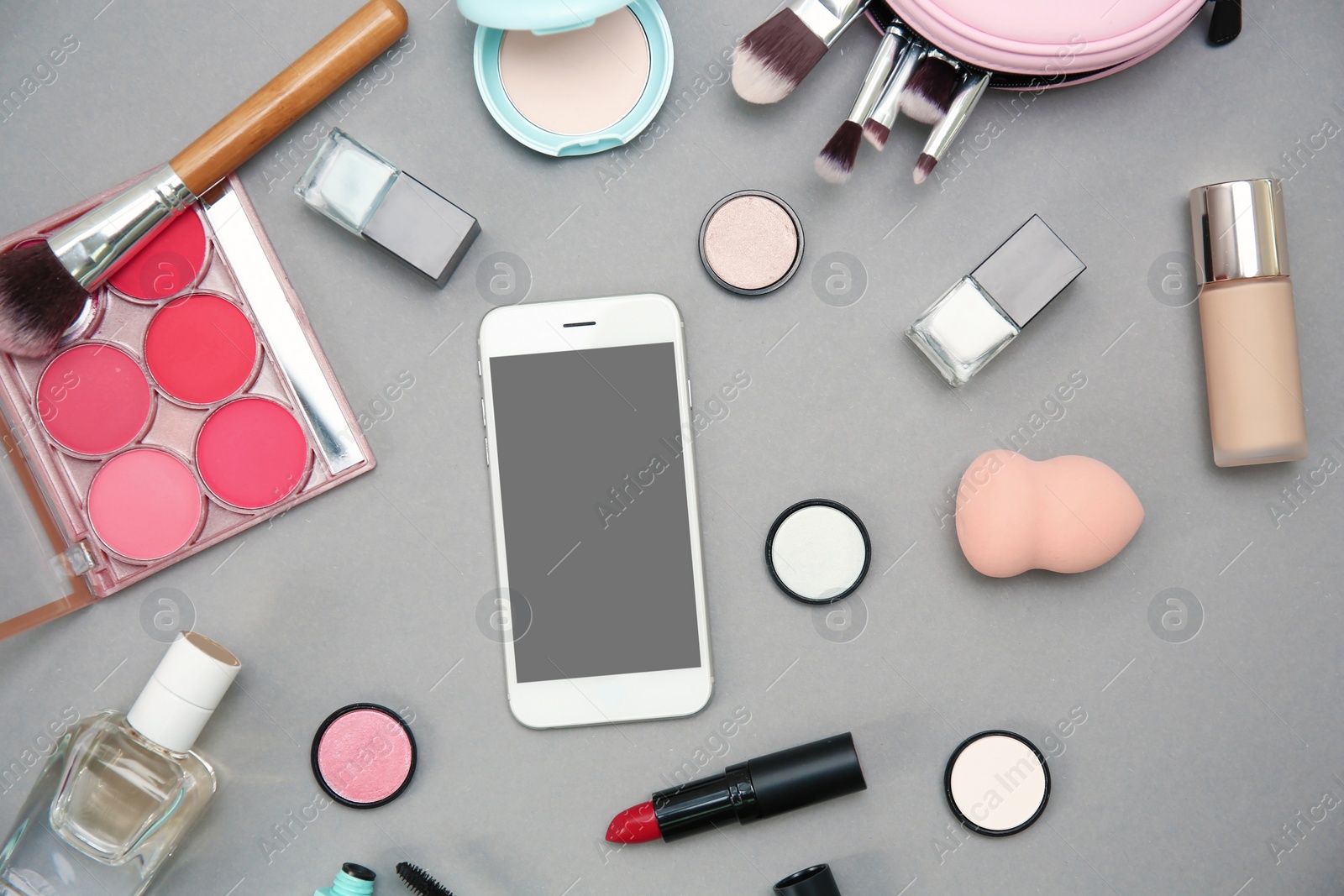 Photo of Flat lay composition with smartphone and makeup products for woman on grey background