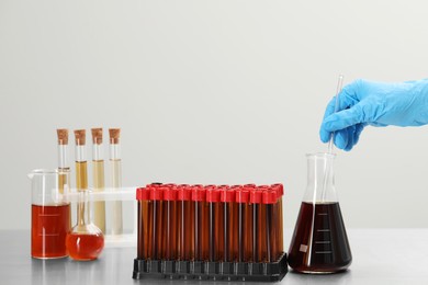 Scientist mixing brown liquid in conical flask against light background, closeup