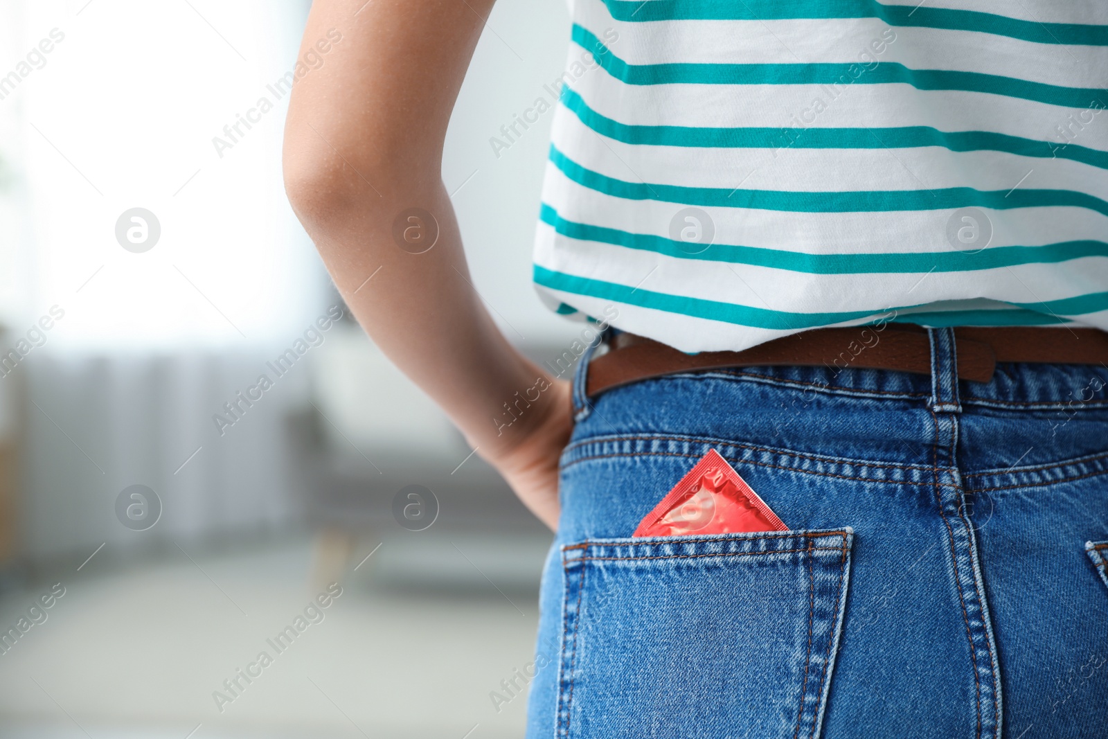 Photo of Woman with condom in pocket of her jeans indoors, closeup. Safe sex concept