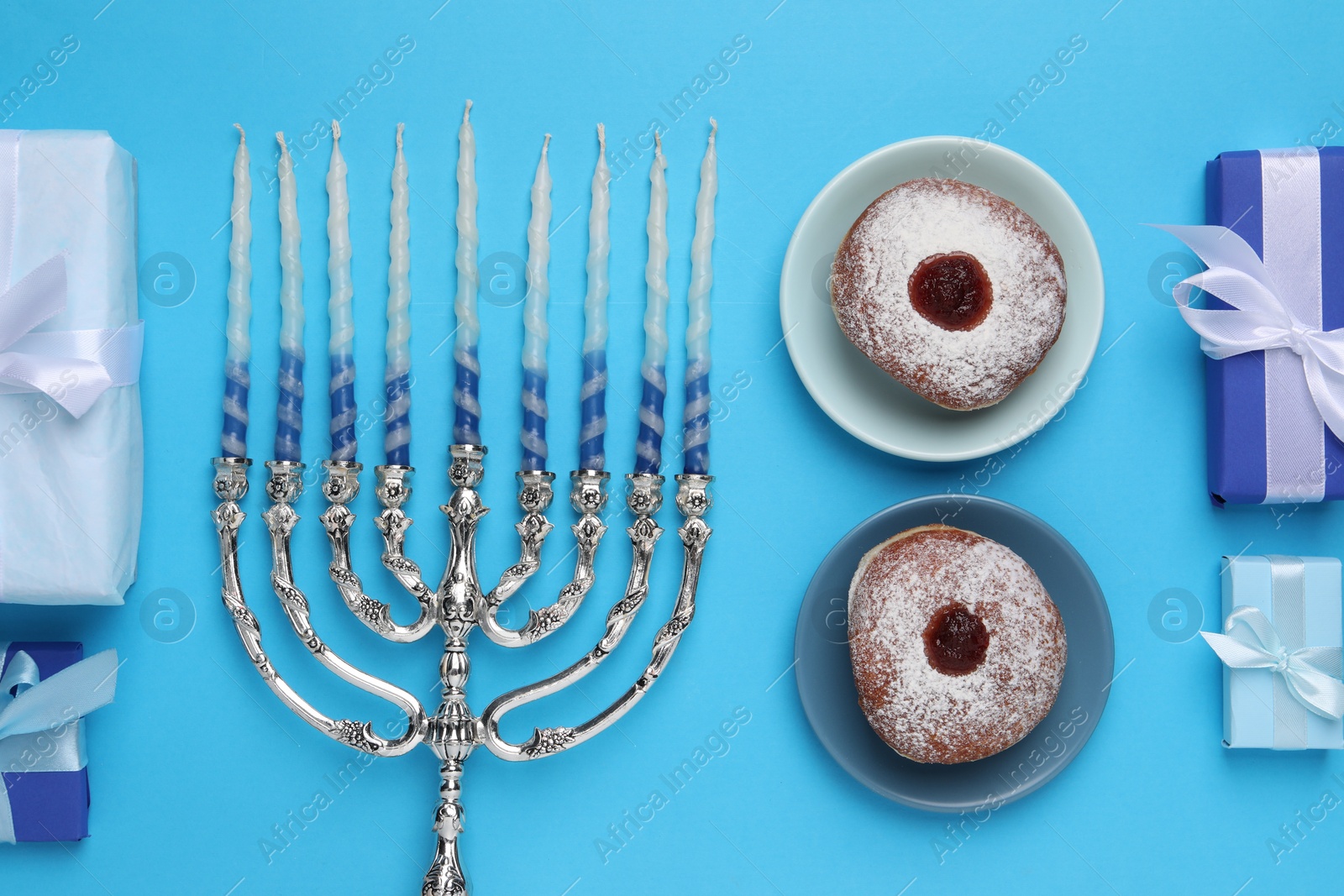 Photo of Flat lay composition with Hanukkah menorah and donuts on light blue background