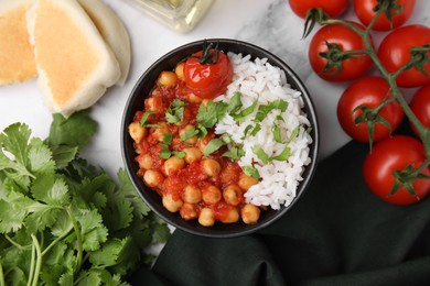 Photo of Delicious chickpea curry in bowl on white marble table, flat lay