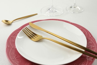 Photo of Stylish setting with cutlery and plates on white textured table, closeup