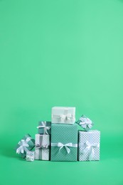 Photo of Many beautifully wrapped gift boxes on green background. Space for text