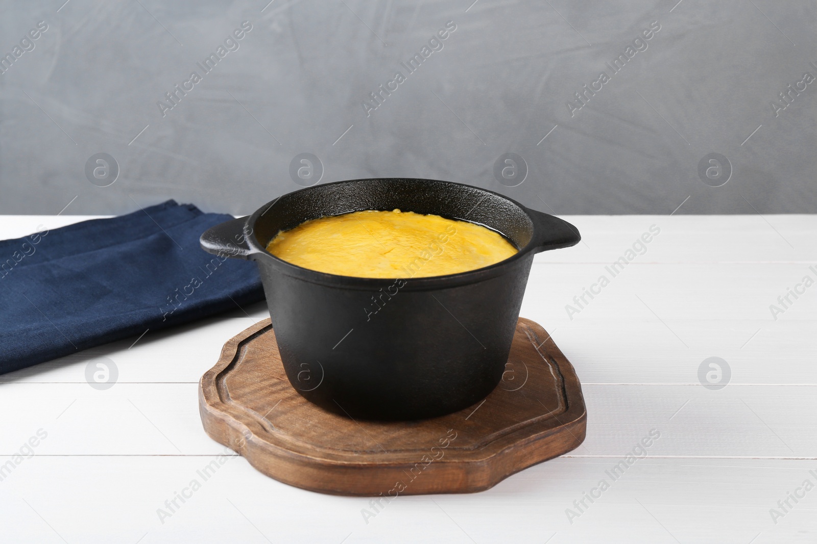 Photo of Fondue with tasty melted cheese on white wooden table