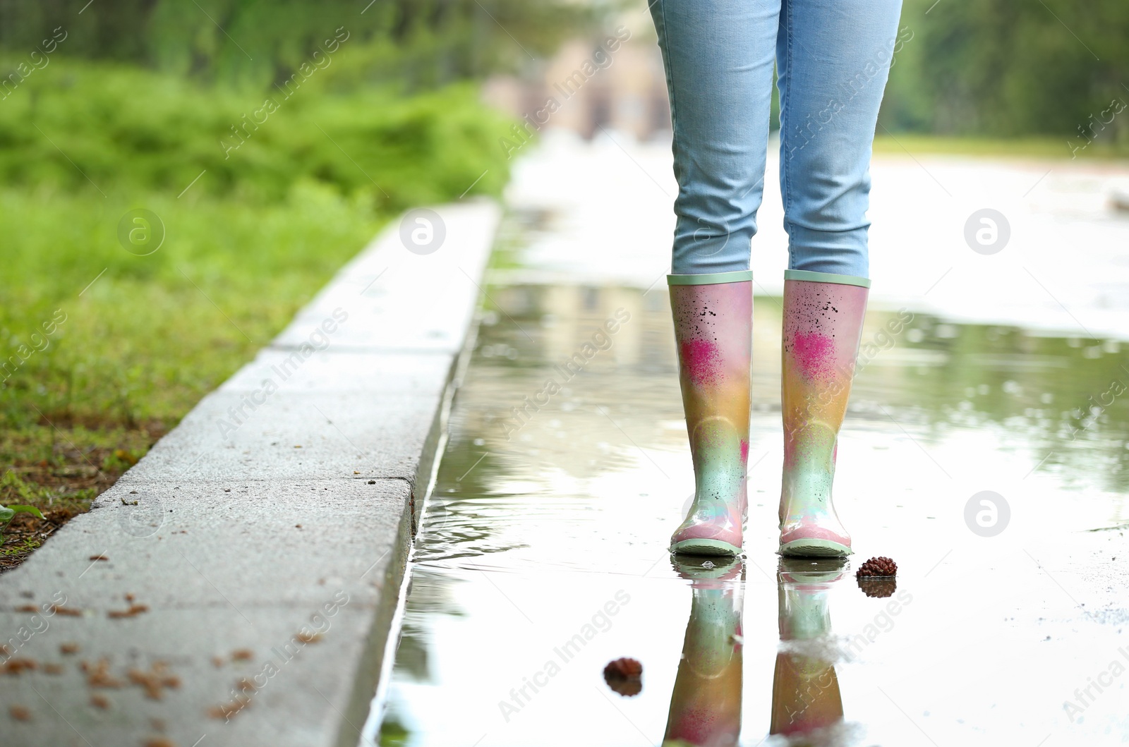 Photo of Woman with rubber boots in puddle, closeup. Rainy weather