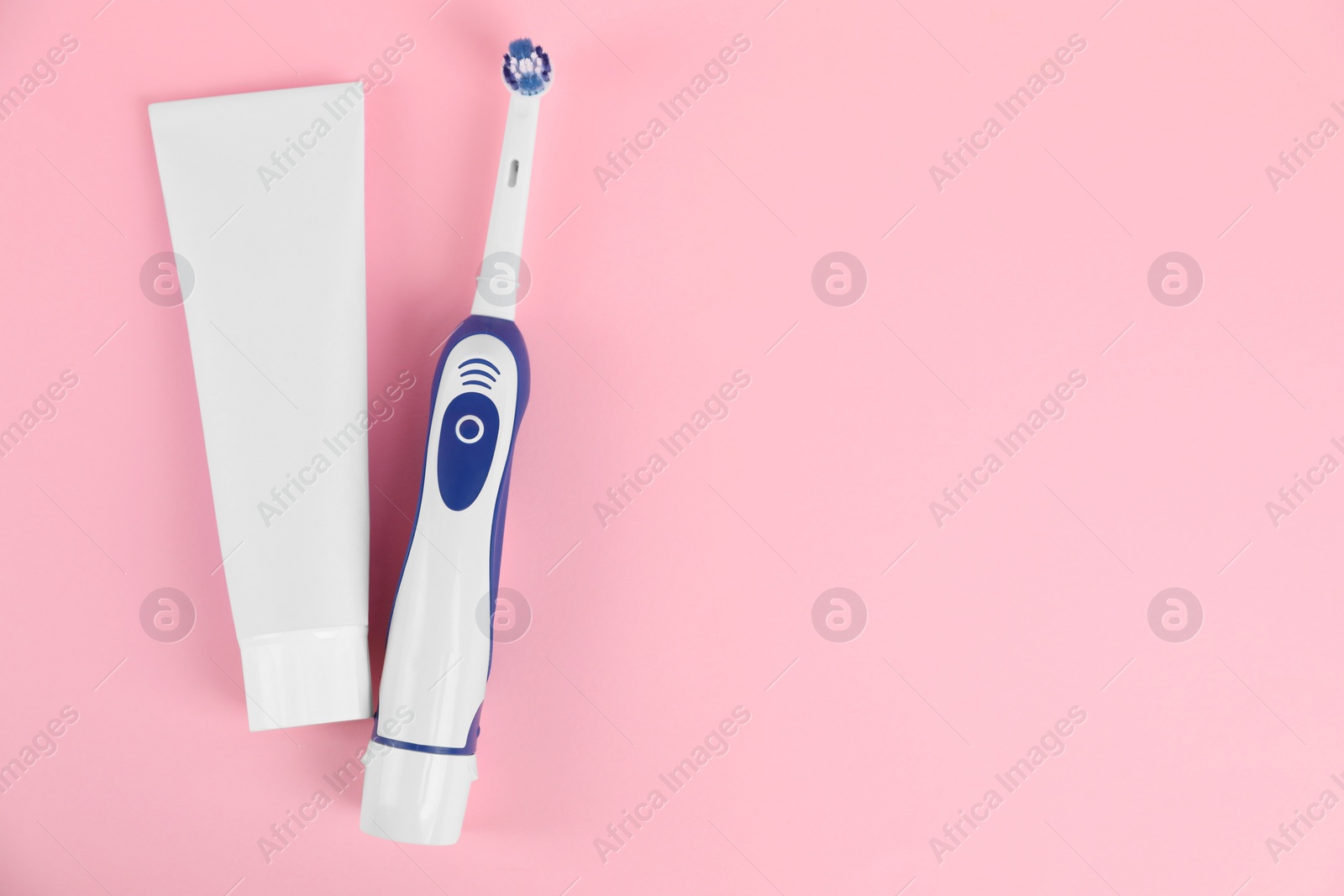 Photo of Electric toothbrush and toothpaste on pink background, flat lay. Space for text