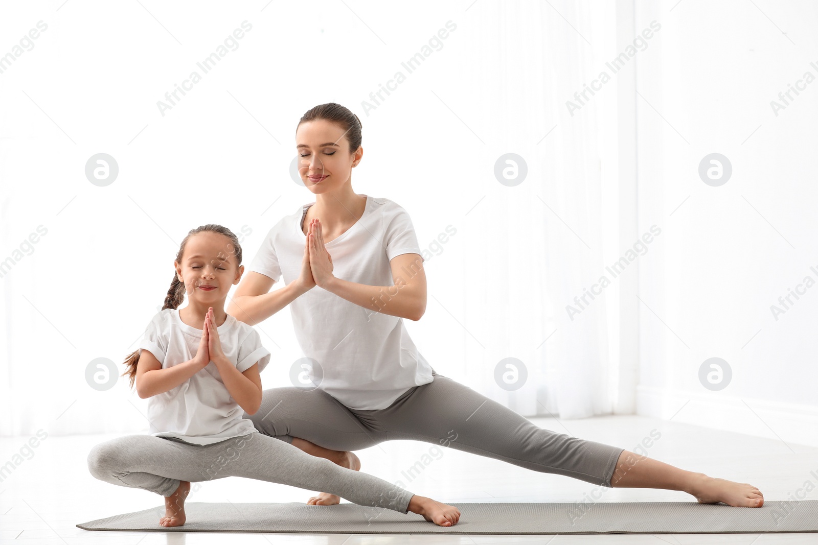 Photo of Young mother with little daughter practicing yoga at home