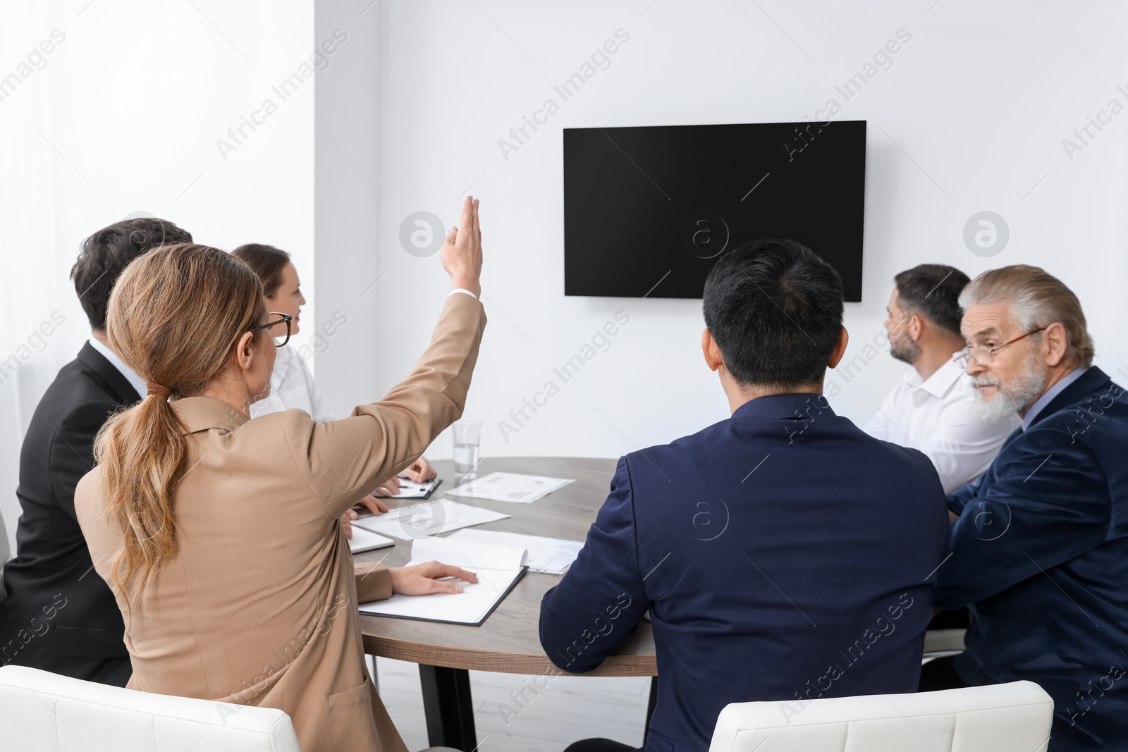 Photo of Business conference. Group of people watching presentation on tv screen in meeting room