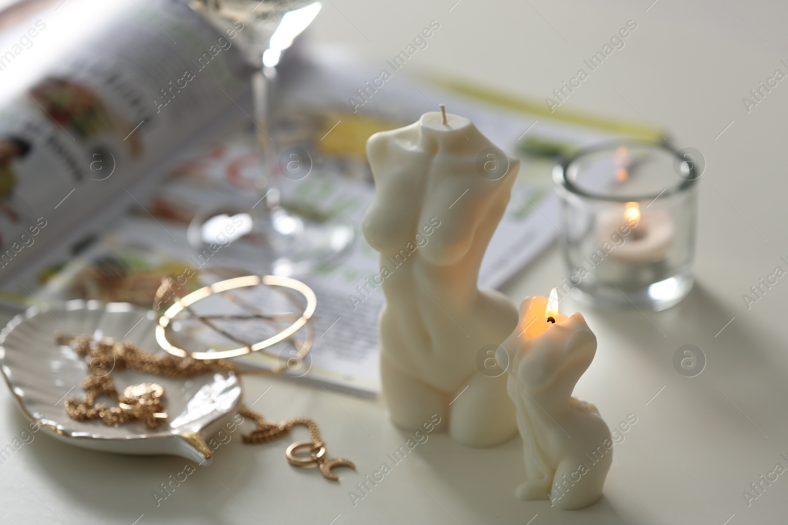 Photo of Beautiful body shaped candles and jewelry on white table indoors, closeup