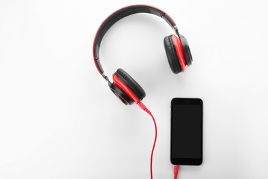 Photo of Smartphone with headphones on white background, top view. Space for text