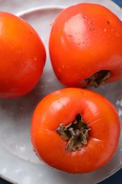 Delicious ripe persimmons on plate, top view