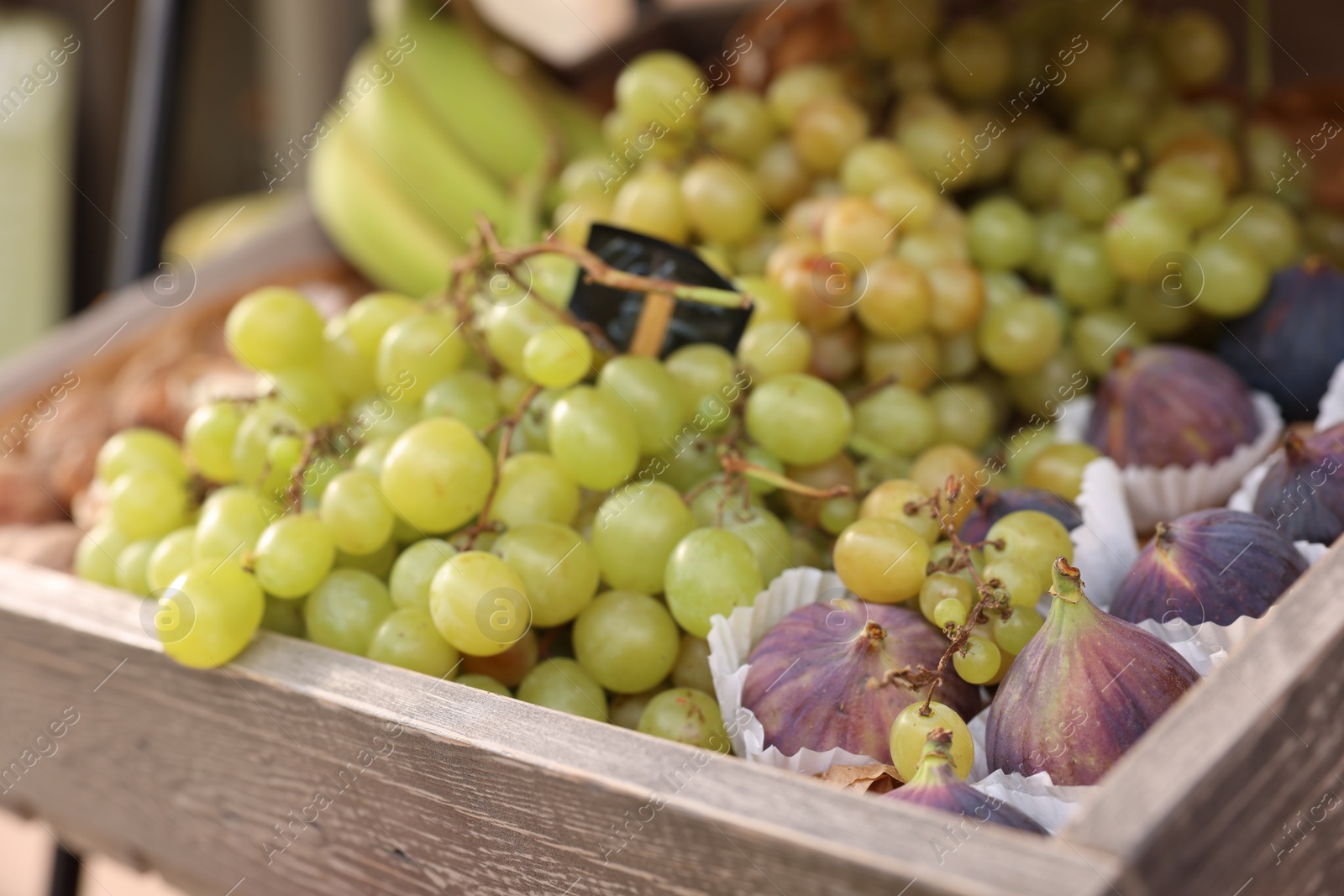 Photo of Fresh ripe fruits in wooden crate at market, selective focus