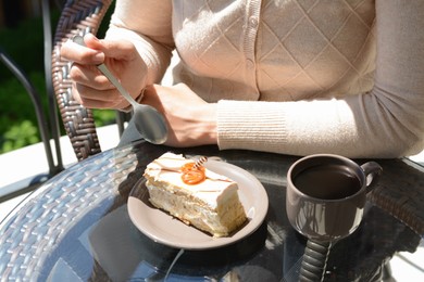 Photo of Woman eating tasty dessert at glass table outdoors, closeup