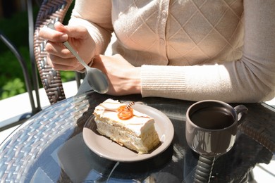 Woman eating tasty dessert at glass table outdoors, closeup