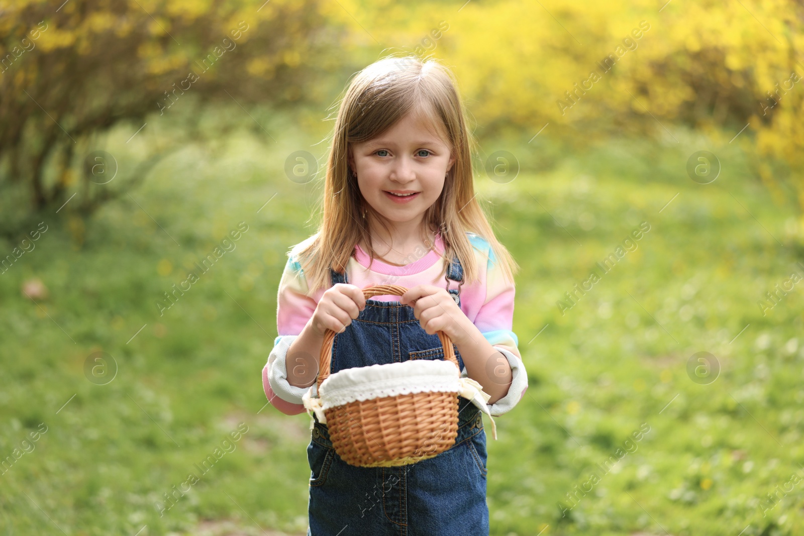 Photo of Easter celebration. Cute little girl with wicker basket outdoors