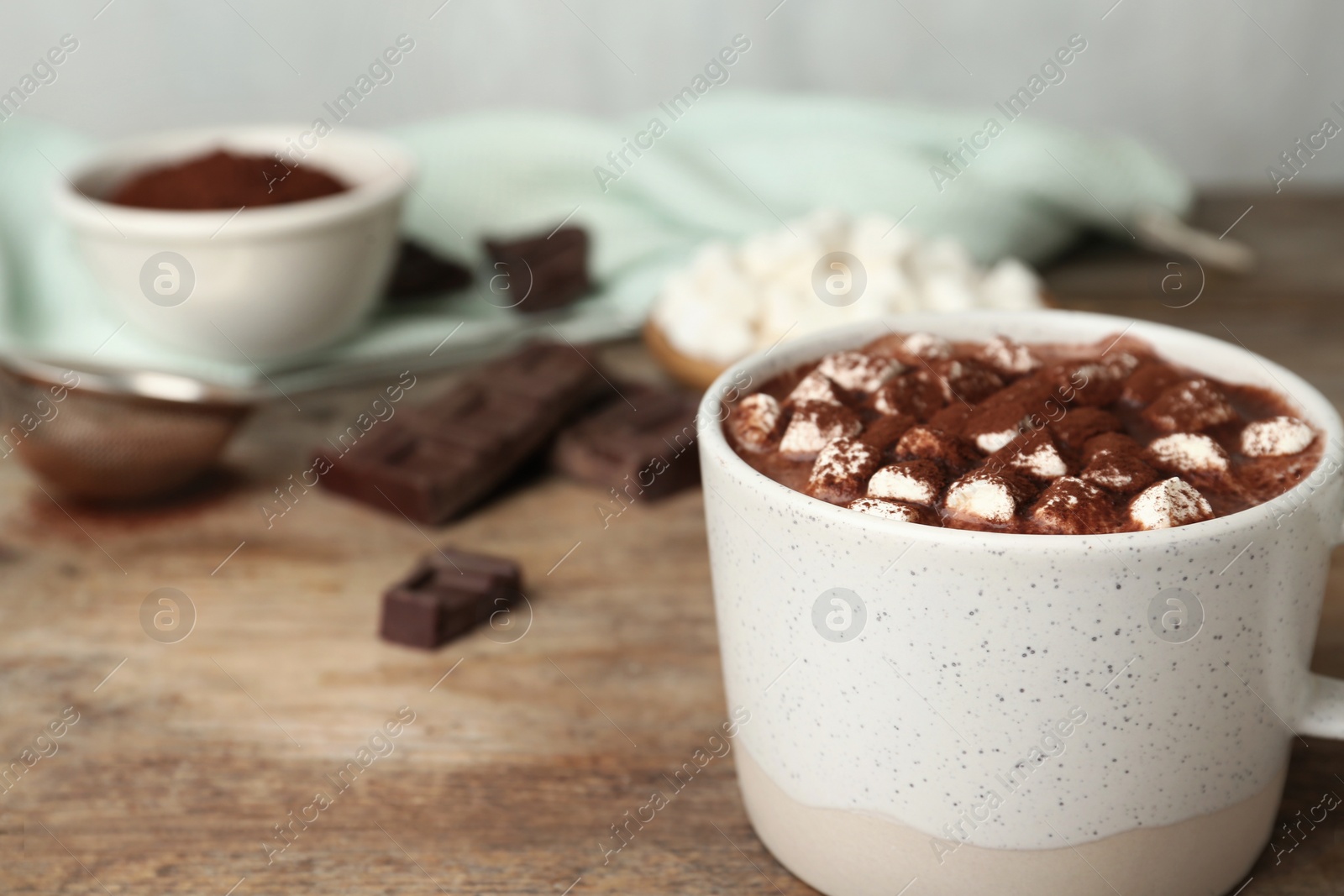 Photo of Delicious cocoa drink with marshmallows in cup on wooden background, closeup. Space for text