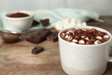 Delicious cocoa drink with marshmallows in cup on wooden background, closeup. Space for text