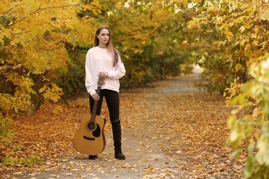 Photo of Teen girl with guitar in autumn park