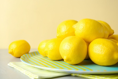 Plate with fresh ripe lemons on table