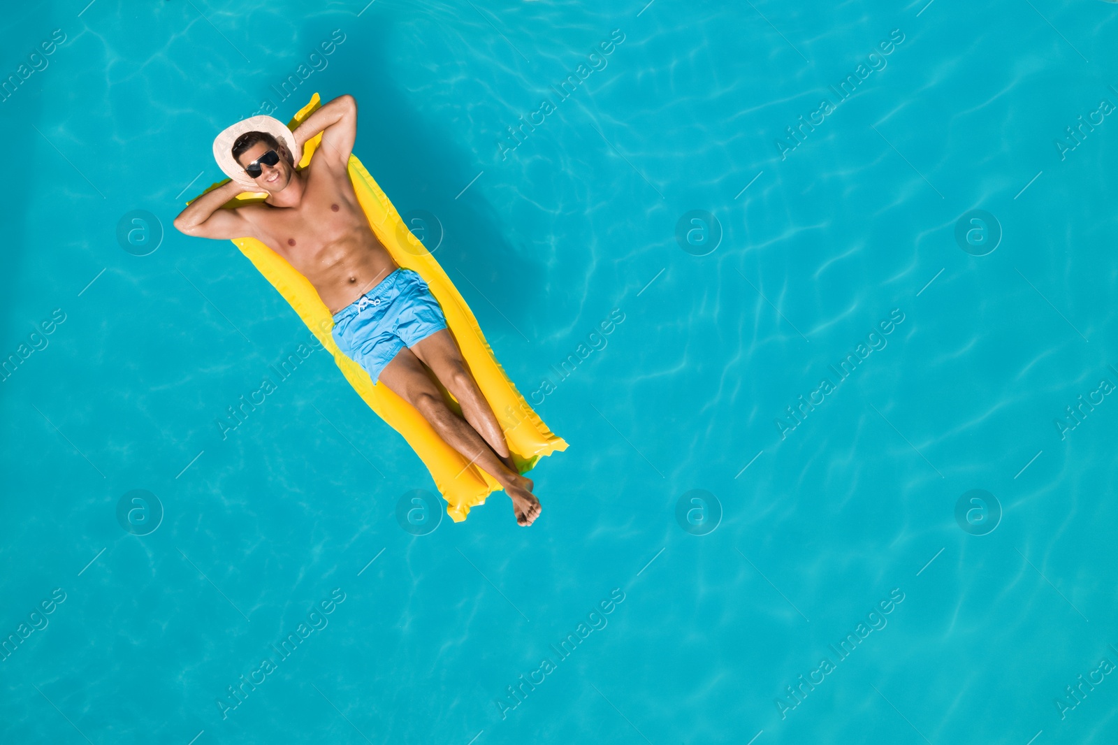 Image of Happy man with inflatable mattress in swimming pool, top view and space for text. Summer vacation