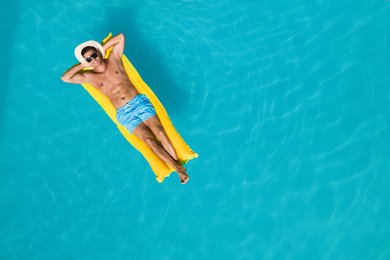 Image of Happy man with inflatable mattress in swimming pool, top view and space for text. Summer vacation